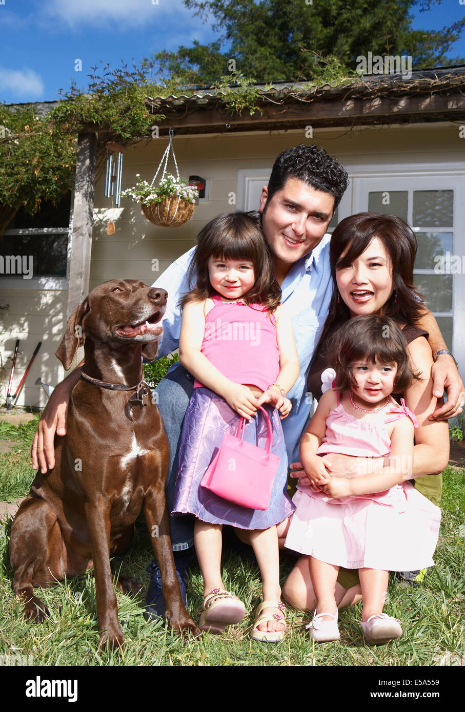 Family smiling together with dog in backyard Stock Photo