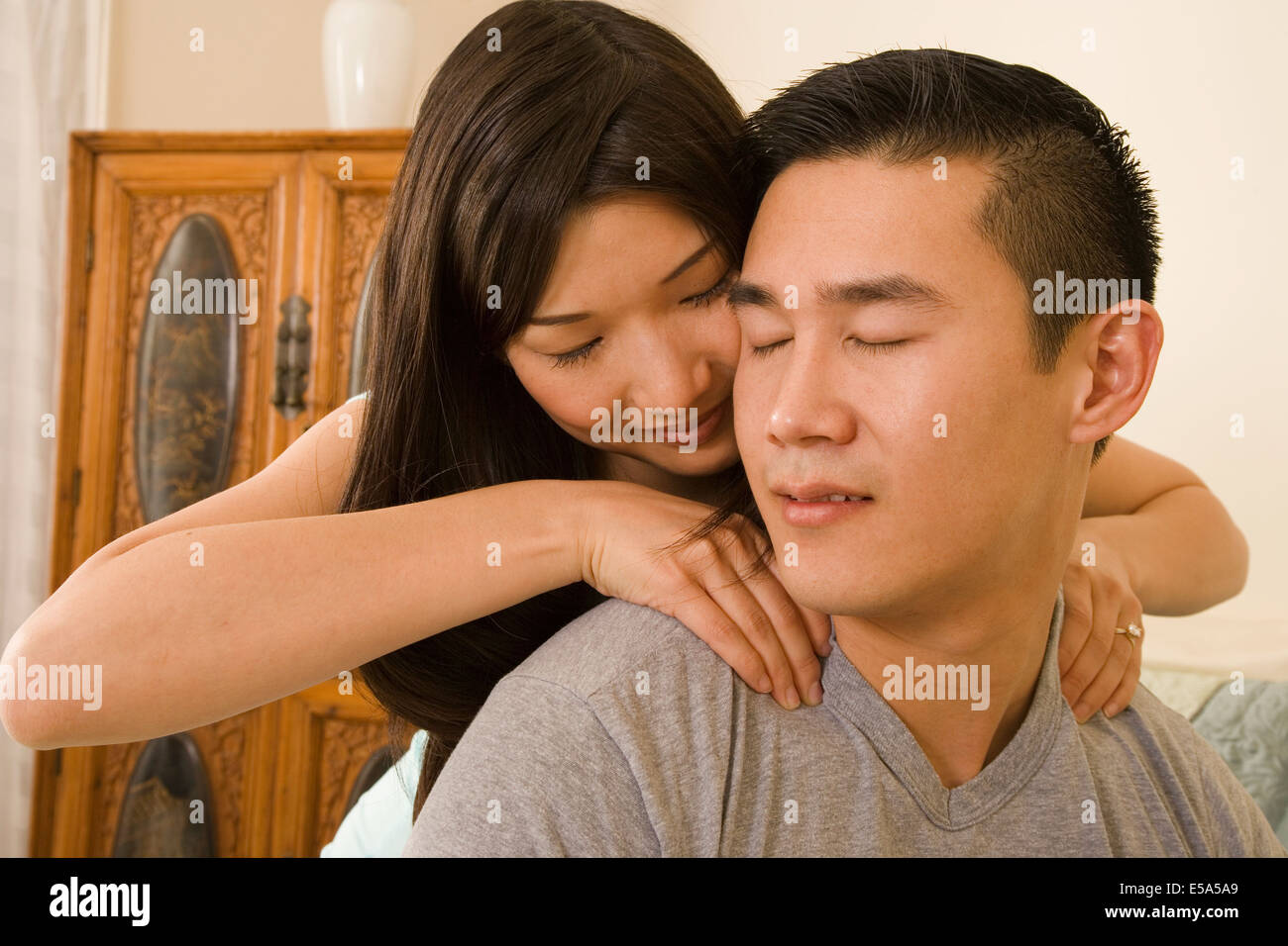 Chinese woman giving boyfriend shoulder massage Stock Photo