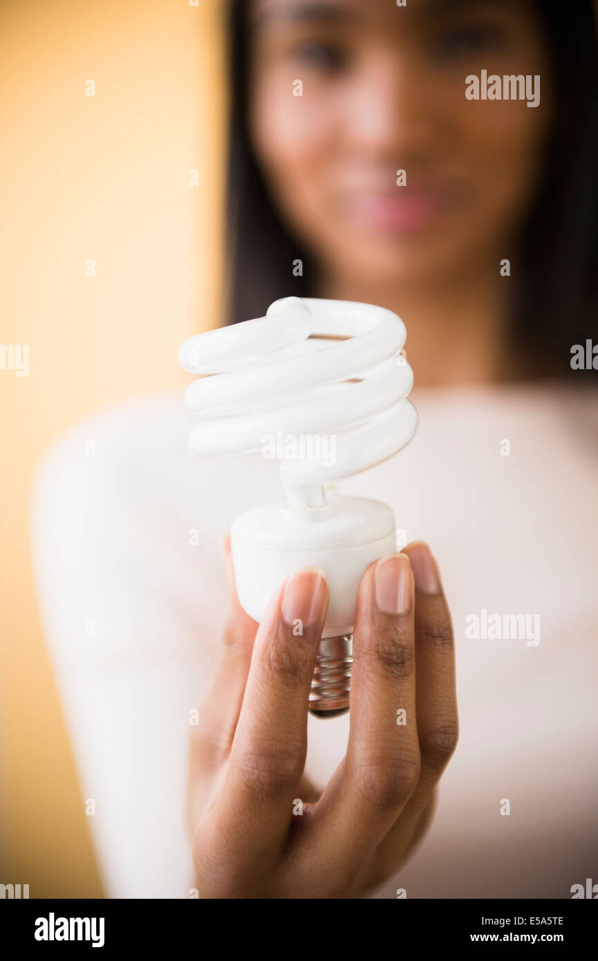 Mixed race woman holding light bulb Stock Photo