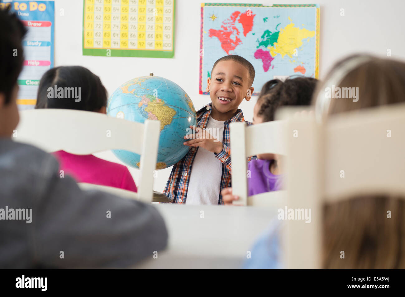Boy showing globe to classroom Stock Photo