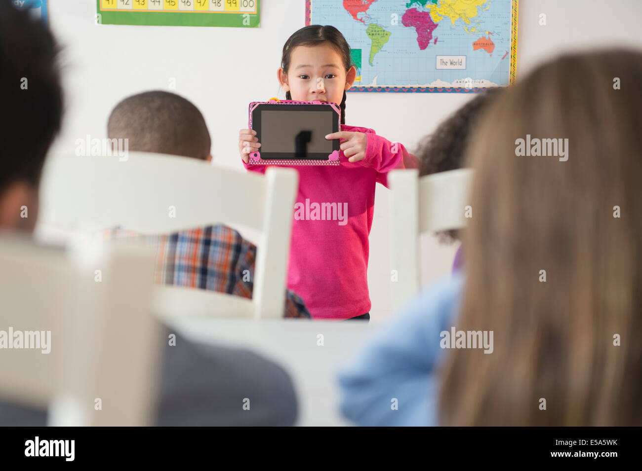Girl showing digital tablet to classroom Stock Photo