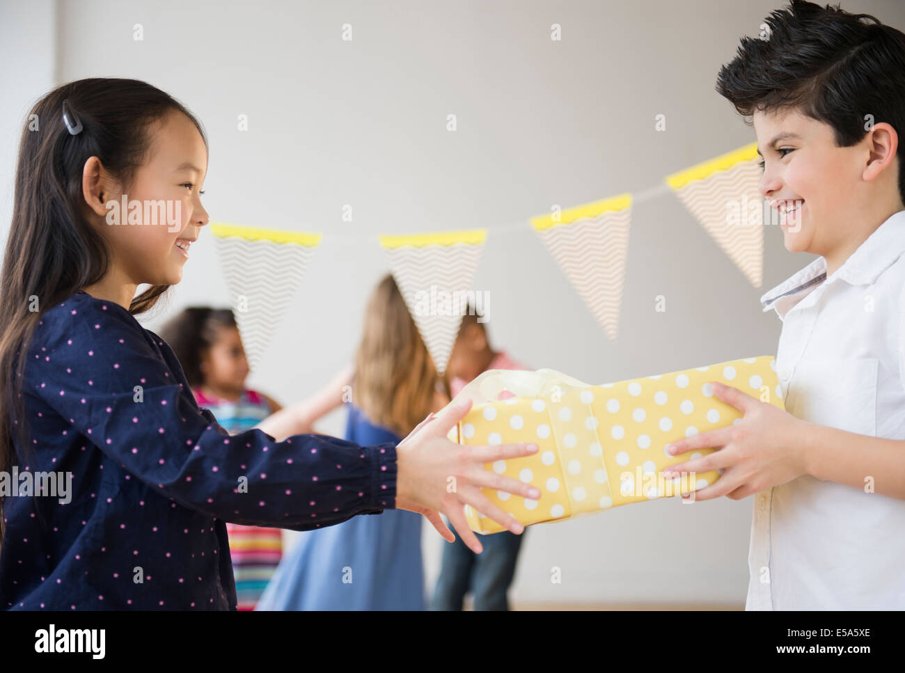 Boy giving girl birthday present at party Stock Photo