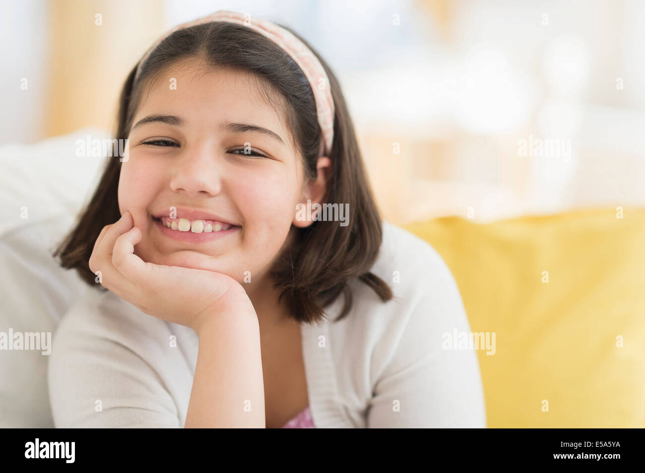 Hispanic girl smiling on sofa Stock Photo - Alamy