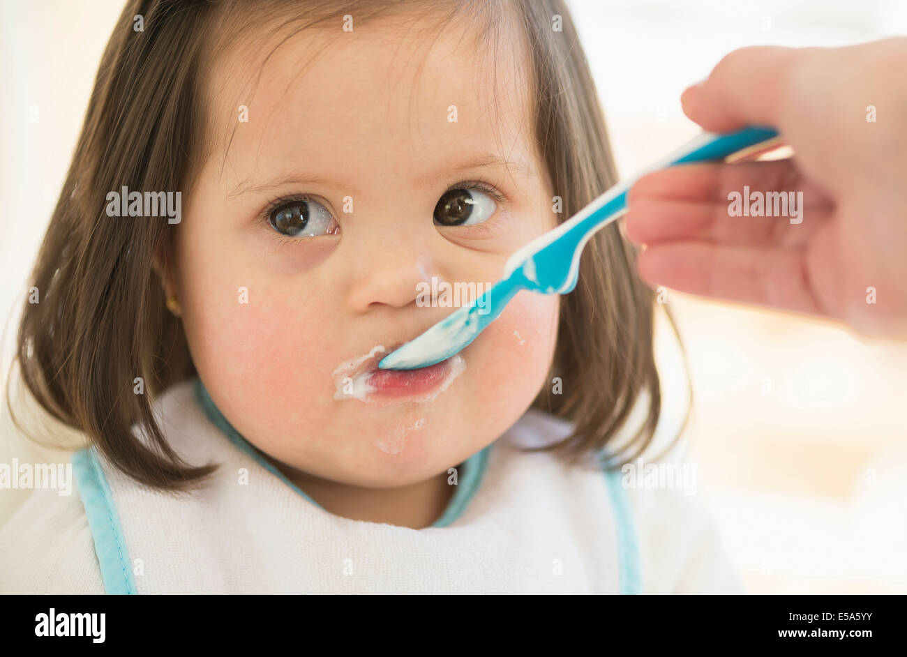 Hispanic mother feeding toddler Stock Photo