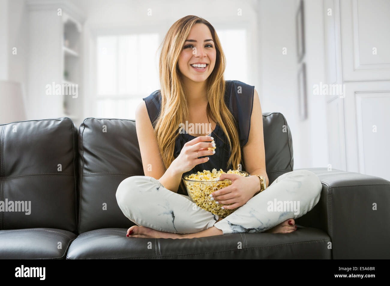 Mixed race woman watching television on sofa Stock Photo