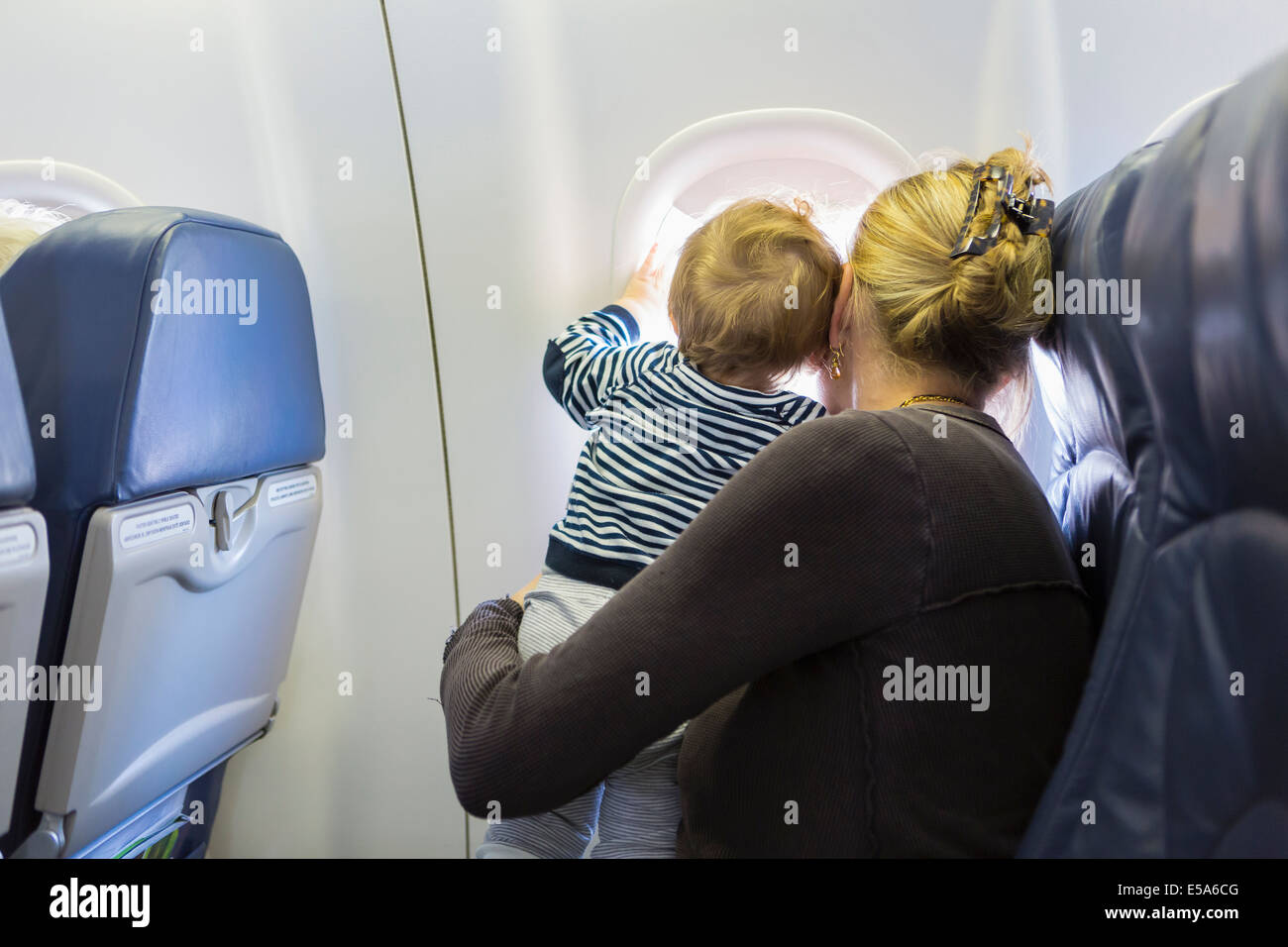 Caucasian mother and baby looking out airplane window Stock Photo