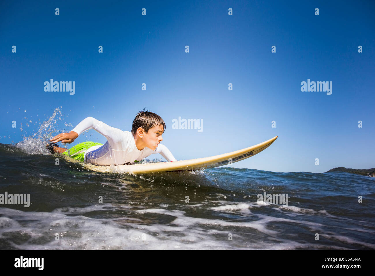 Mixed race boy surfing in ocean Stock Photo