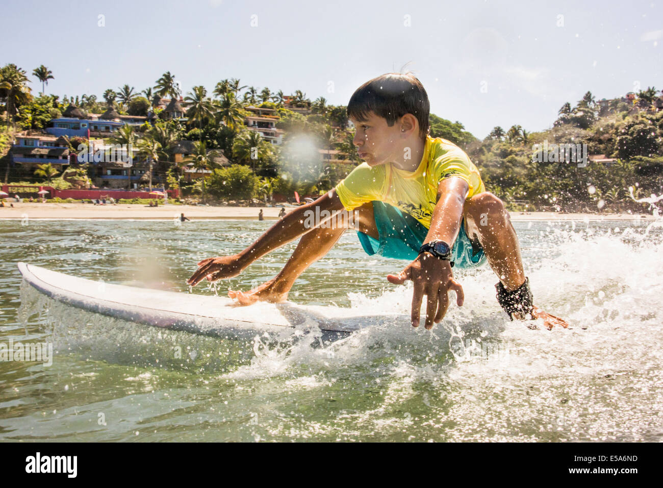 Mixed race boy surfing in ocean Stock Photo