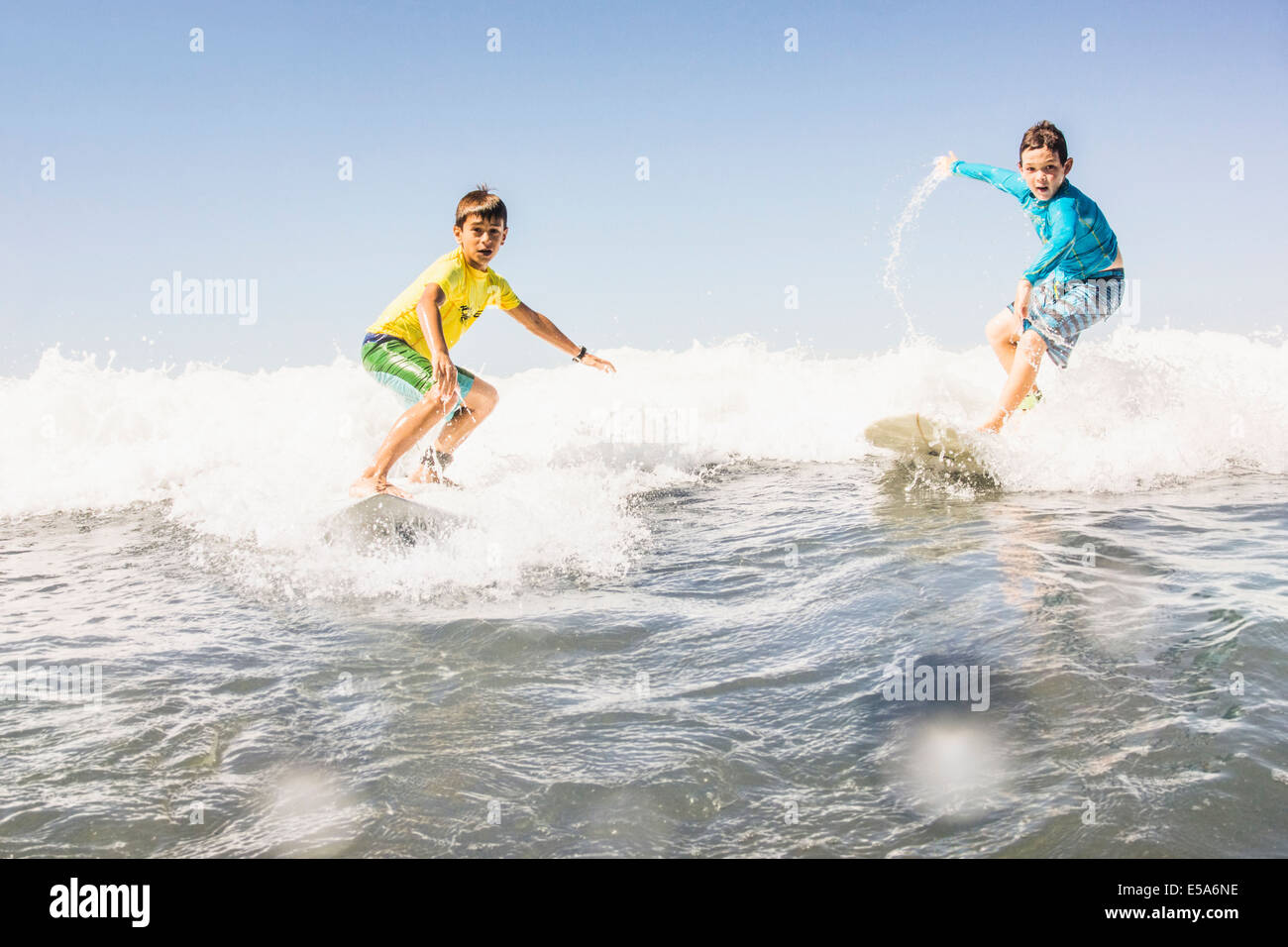 Boys surfing in ocean Stock Photo