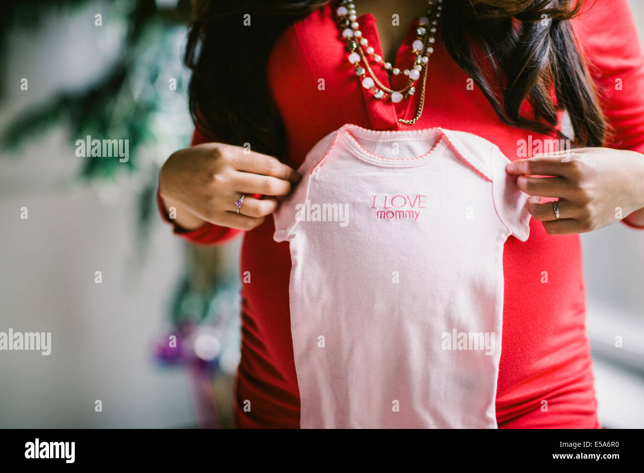 Pregnant Asian woman holding baby clothes Stock Photo