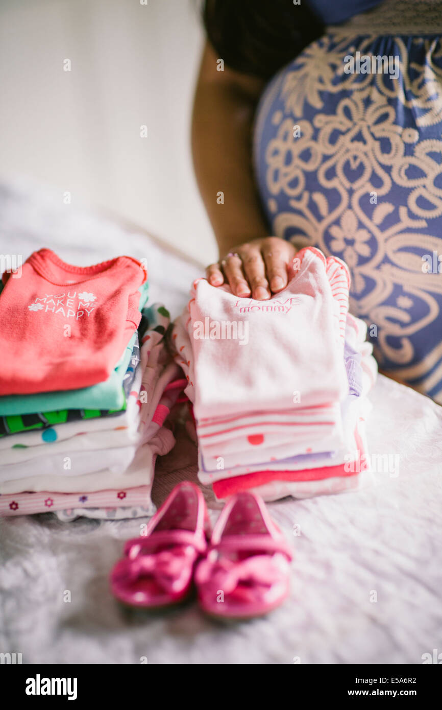 Pregnant Asian woman folding baby clothes Stock Photo