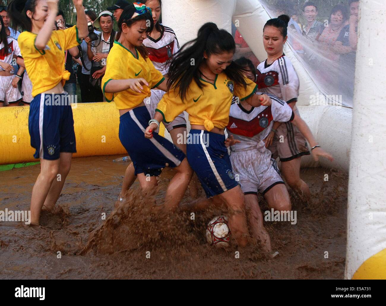 Two groups of girls wearing Germany national football team jersey and Brazil national team jersey play mud football on July 13, 2014 in Xi'an, Shaanxi province of China.Mud football was originated from Finland, and it has become more and more popular in China. Stock Photo