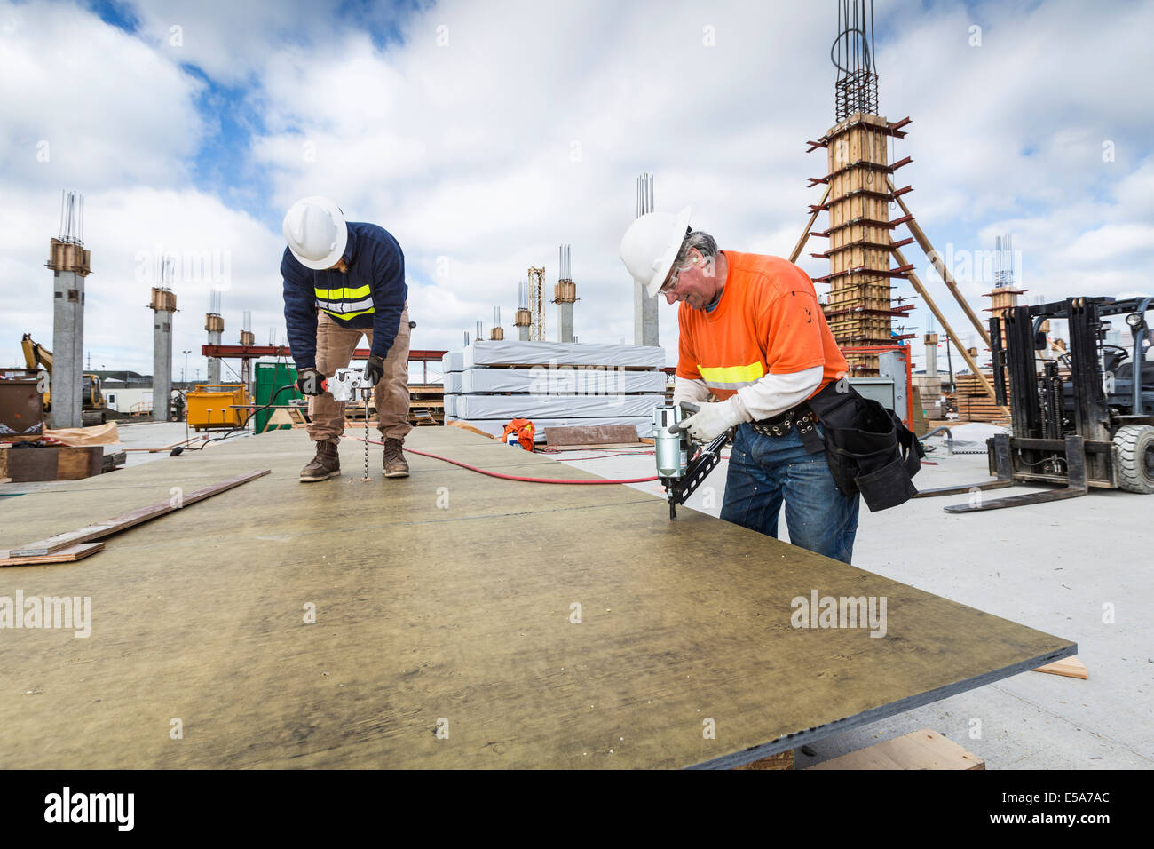 Caucasian workers drilling plant at construction site Stock Photo