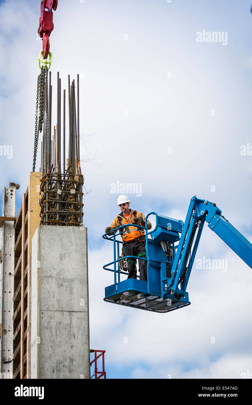 Caucasian worker standing on boom lift on site Stock Photo