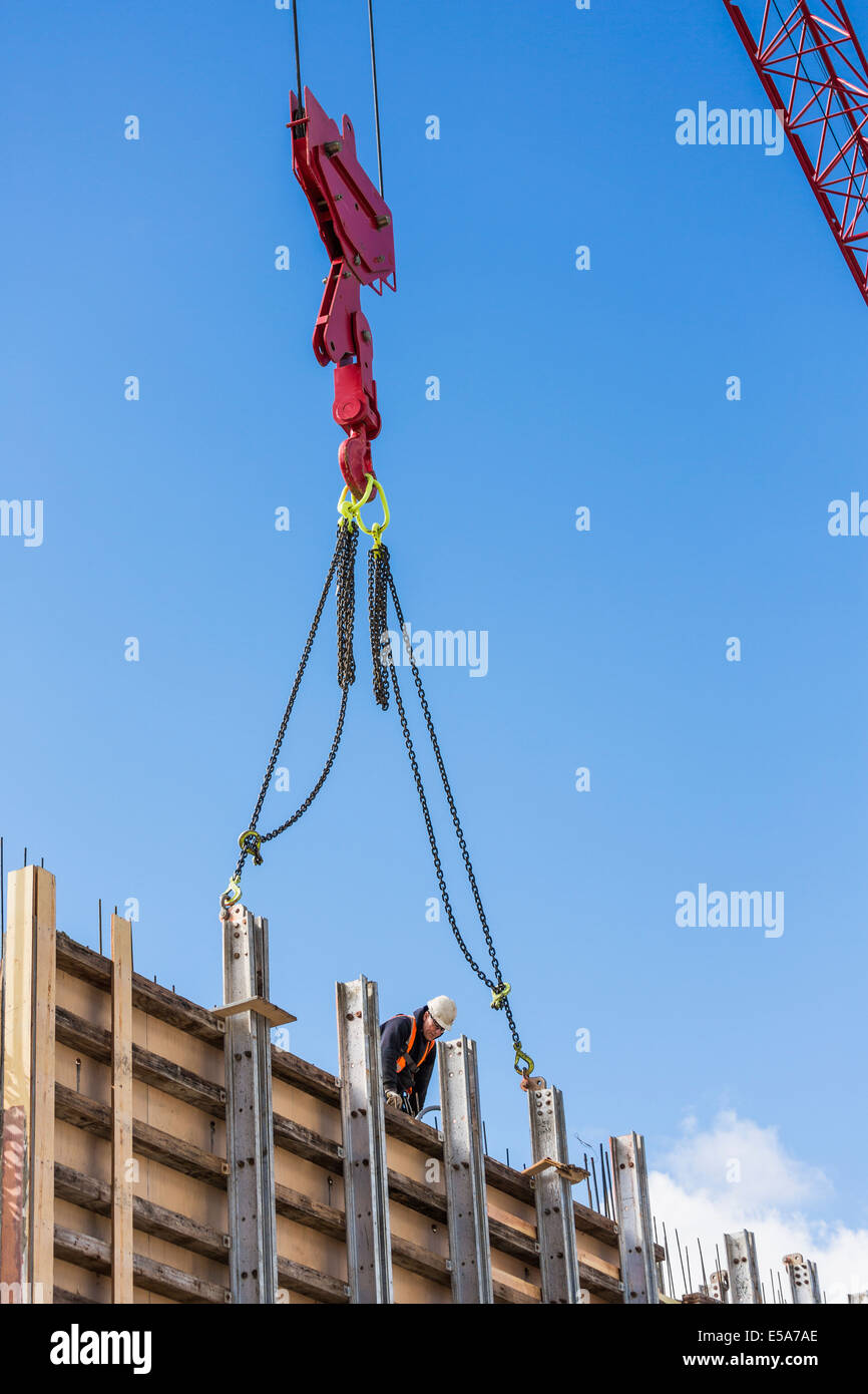 Crane attached to concrete wall form on construction site Stock Photo