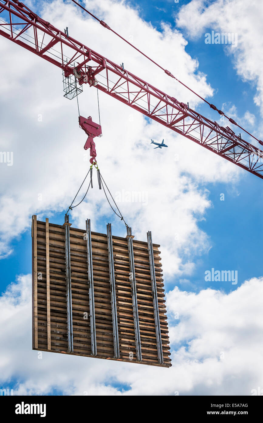 Crane lifting concrete wall form on construction site Stock Photo