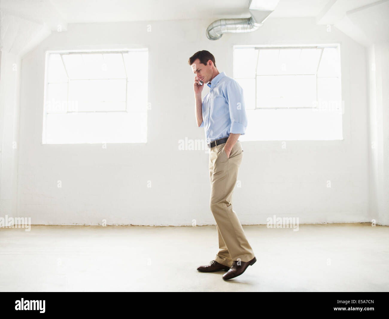 Caucasian businessman talking on cell phone in empty office Stock Photo