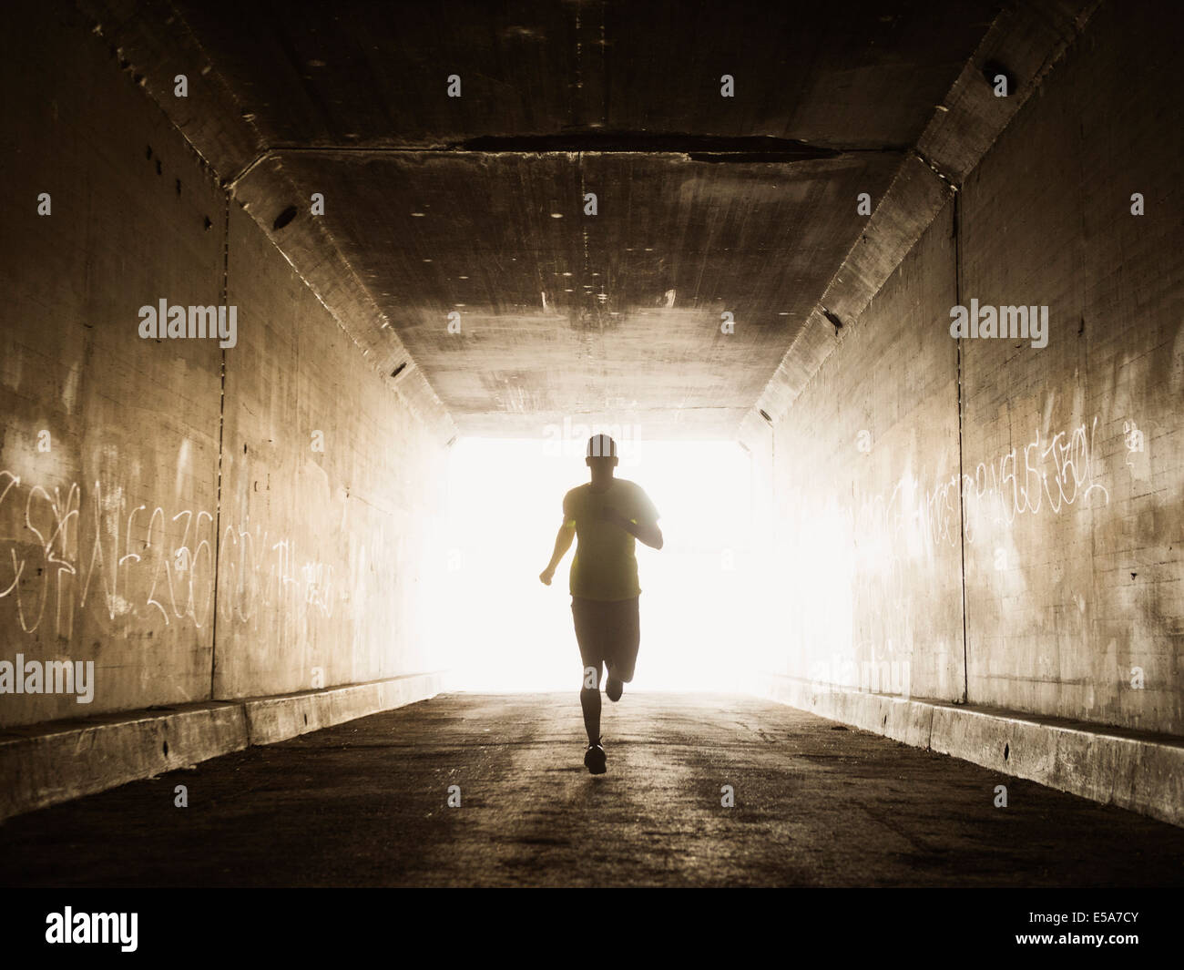 Caucasian man running in urban tunnel Stock Photo