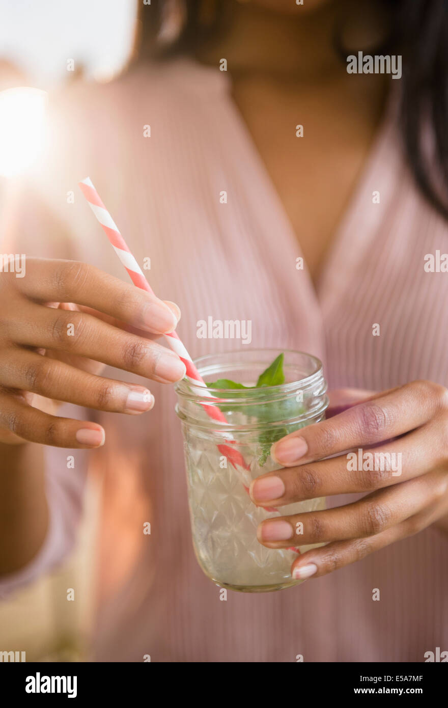 Mixed race woman drinking cocktail Stock Photo