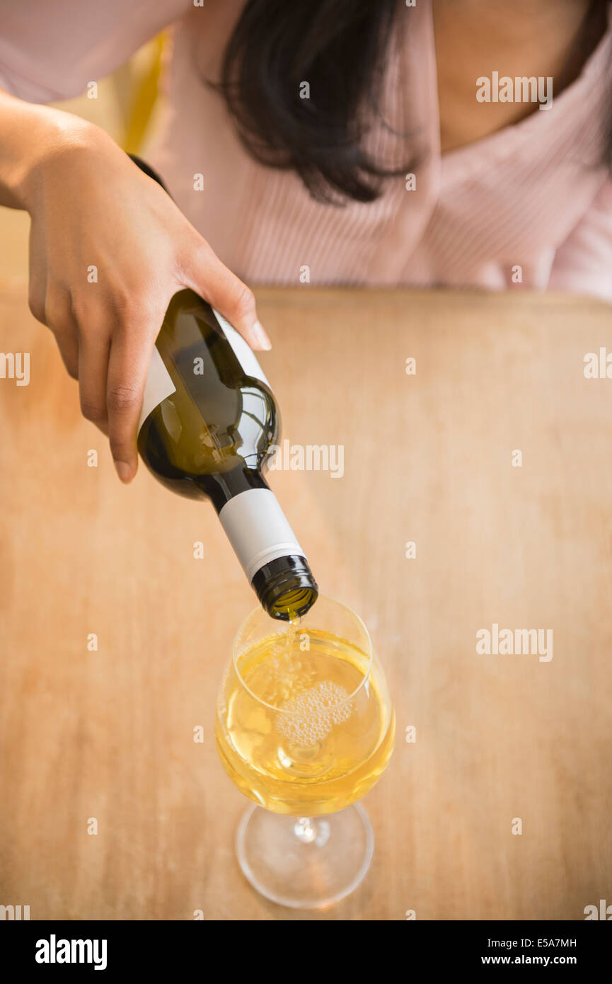 Mixed race woman pouring glass of wine Stock Photo