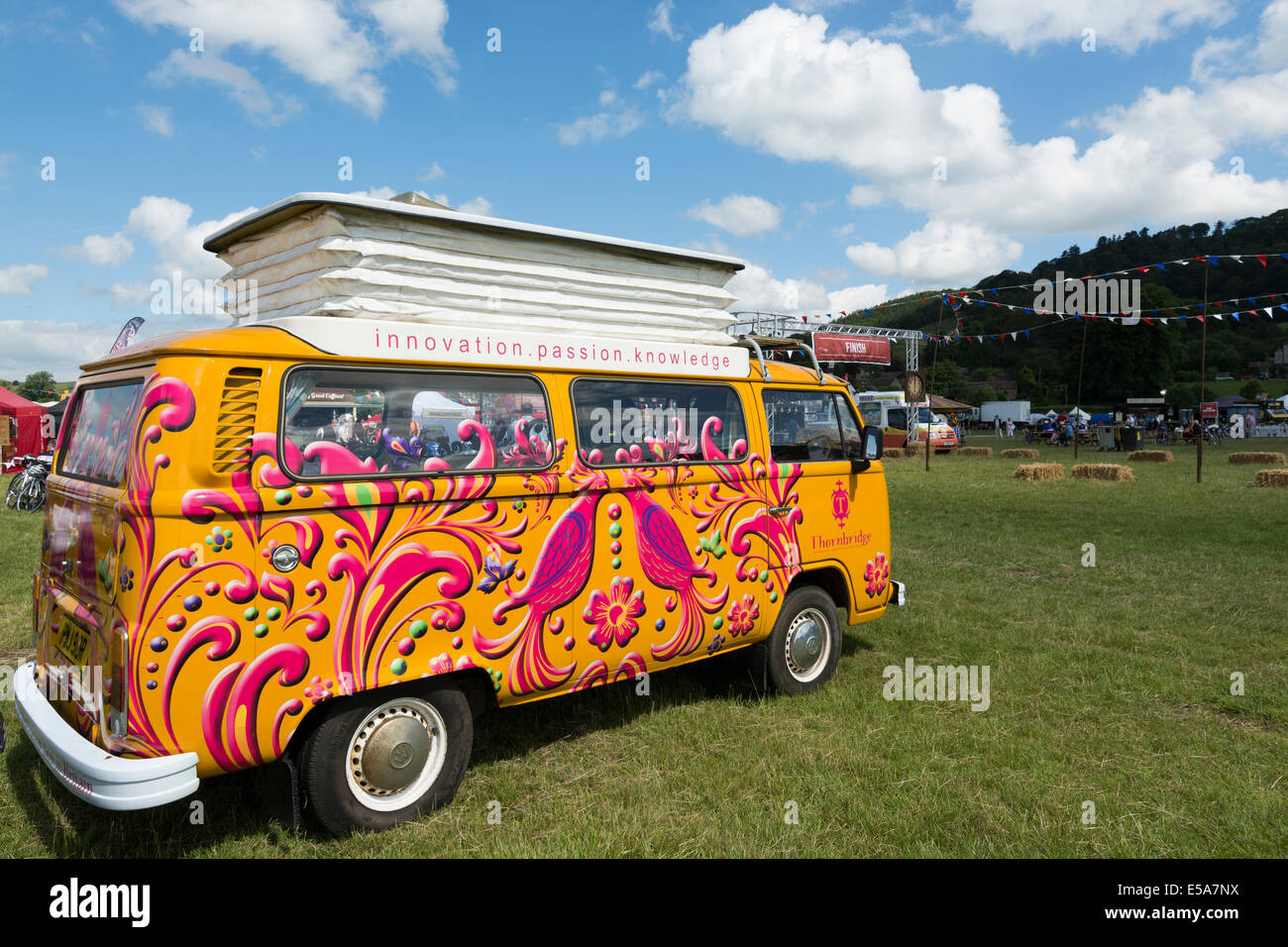 Brightly colored/painted VW camper van in field during show Bakewell Derbyshire England Stock Photo