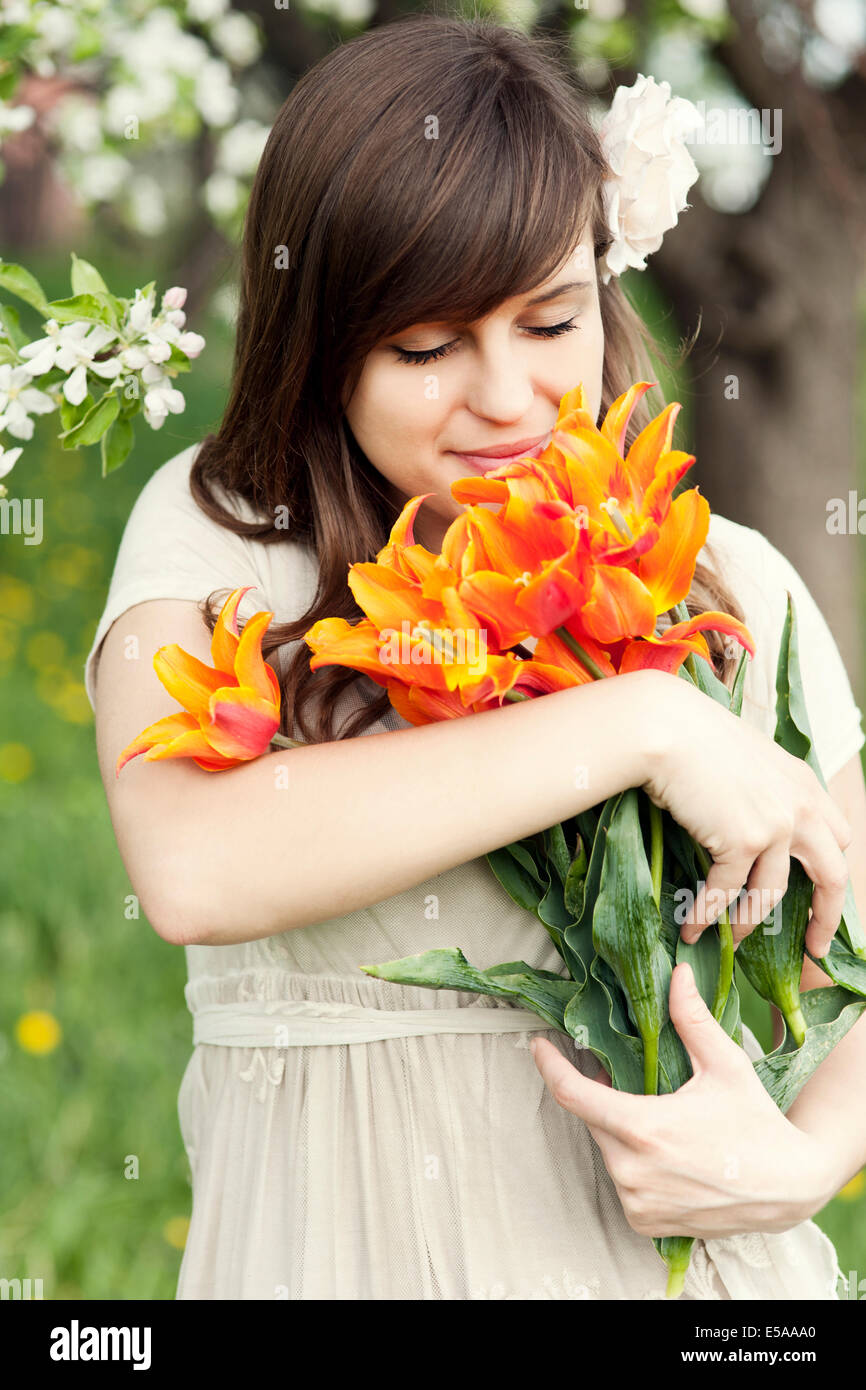 Happy young woman enjoying the fragrance of flowers. Debica, Poland. Stock Photo