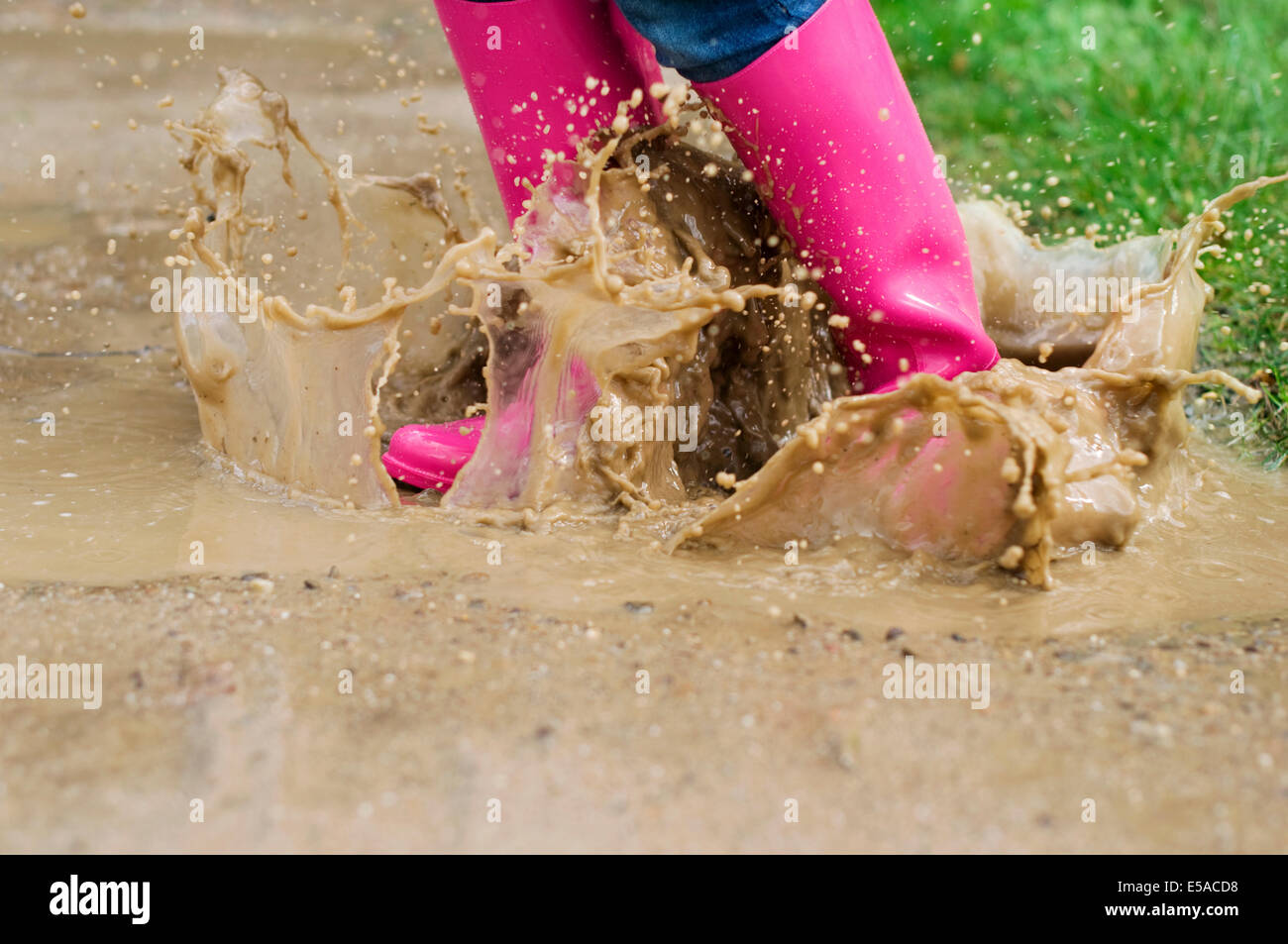 Young woman with rubber boots jumping in puddle, Debica, Poland. Stock Photo