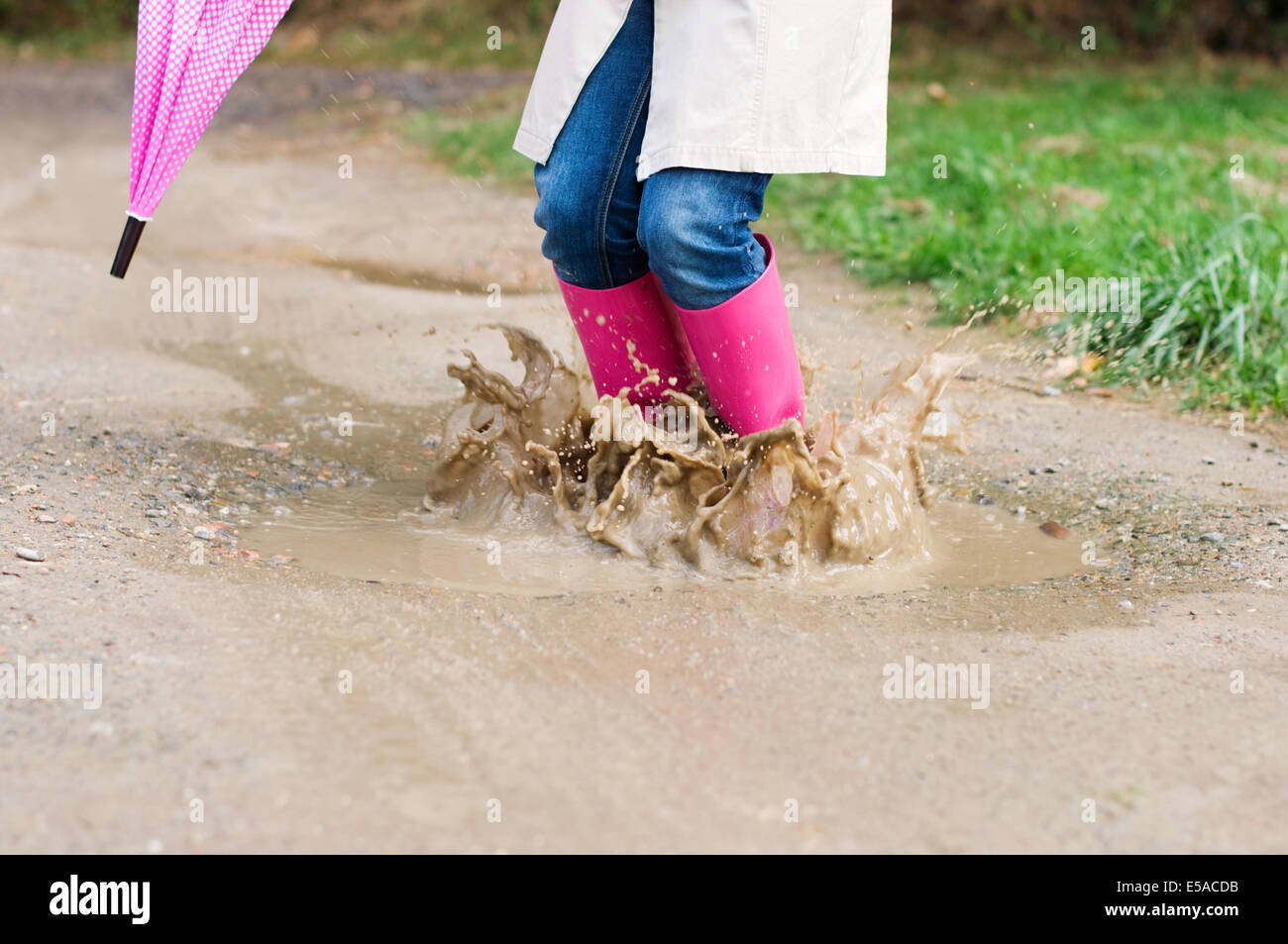 Young woman with rubber boots jumping, puddle, Debica, Poland. Stock Photo