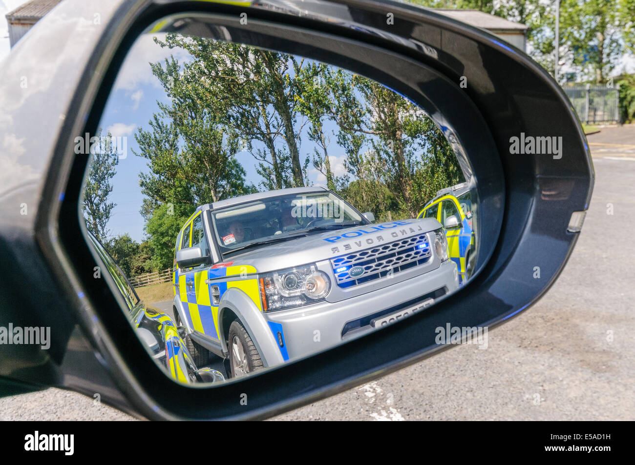 A police Landrover with flashing lights in the door mirror of a car (see also E5D39J) Stock Photo