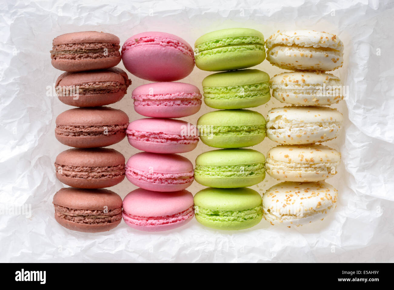 Food: multicolored macarons assortment, arranged on white crumpled paper, isolated on white background Stock Photo