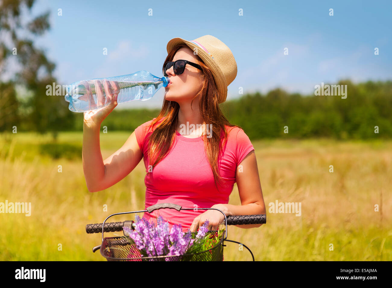 Active woman with bike drinking cold water, Debica, Poland Stock Photo
