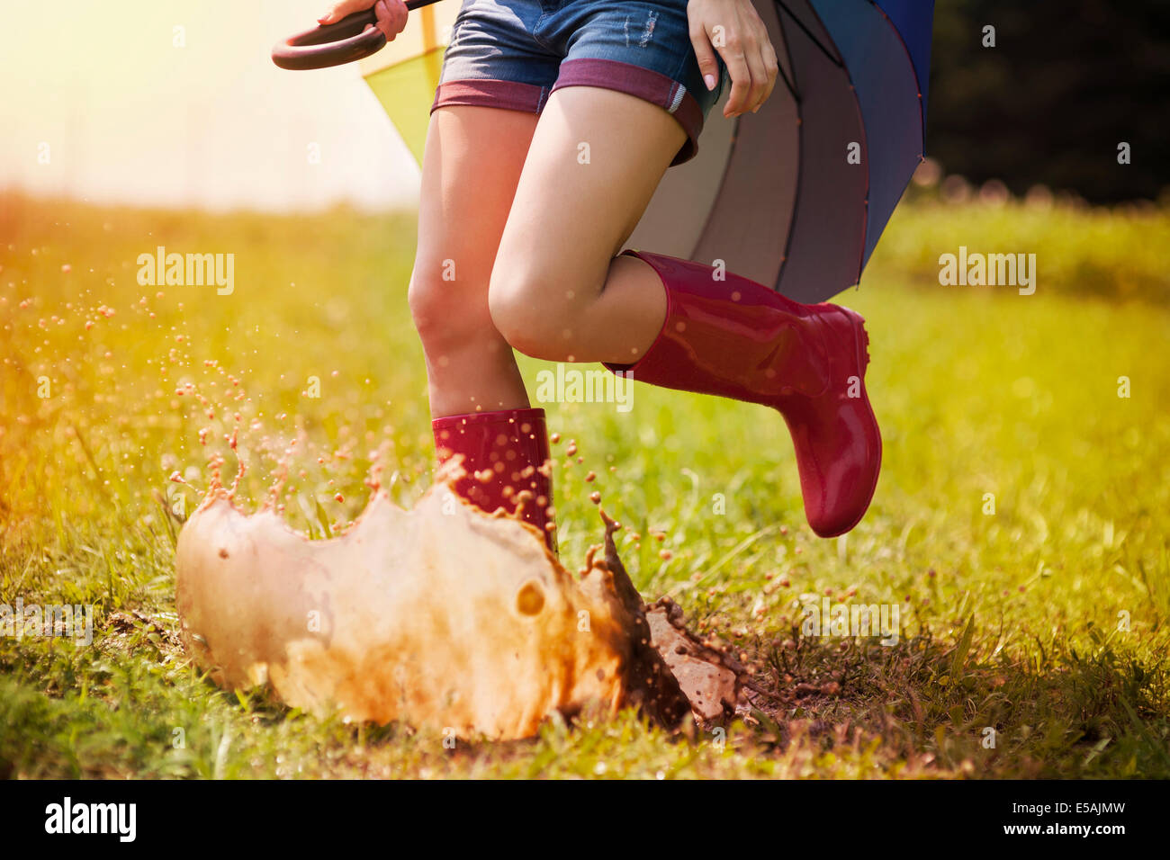 Jumping woman with umbrella and rubber boots, Debica, Poland Stock Photo