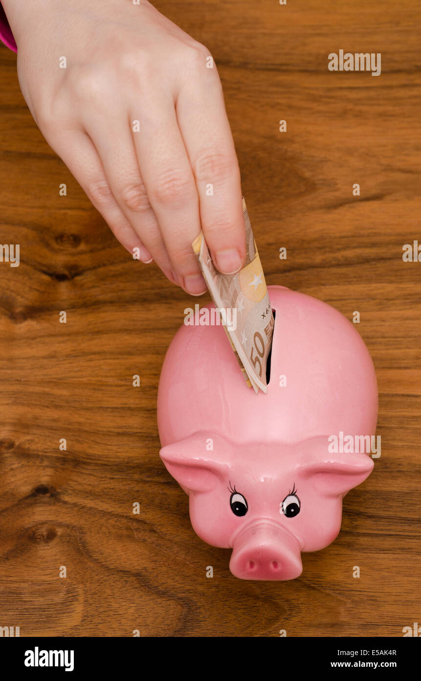 Female hand is putting 50 euro not into a pink piggy bank Stock Photo ...