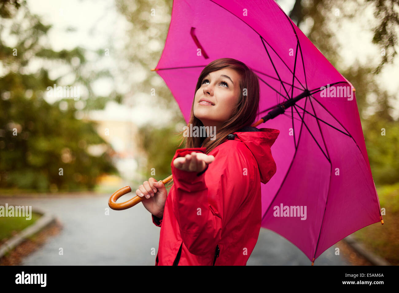 Beautiful woman with umbrella checking for rain, Debica, Poland Stock Photo