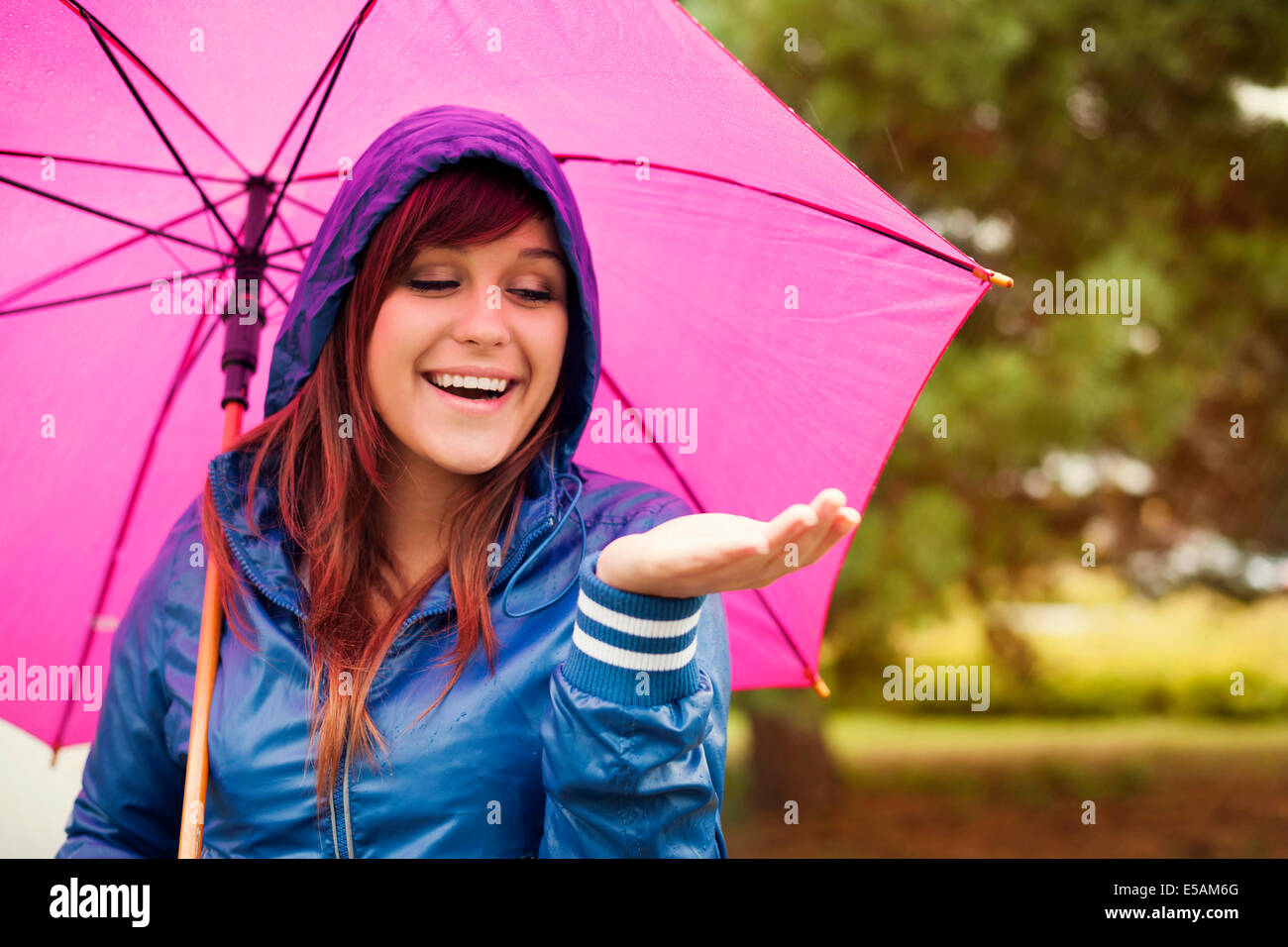 Cheerful woman under pink umbrella checking for rain, Debica, Poland Stock Photo