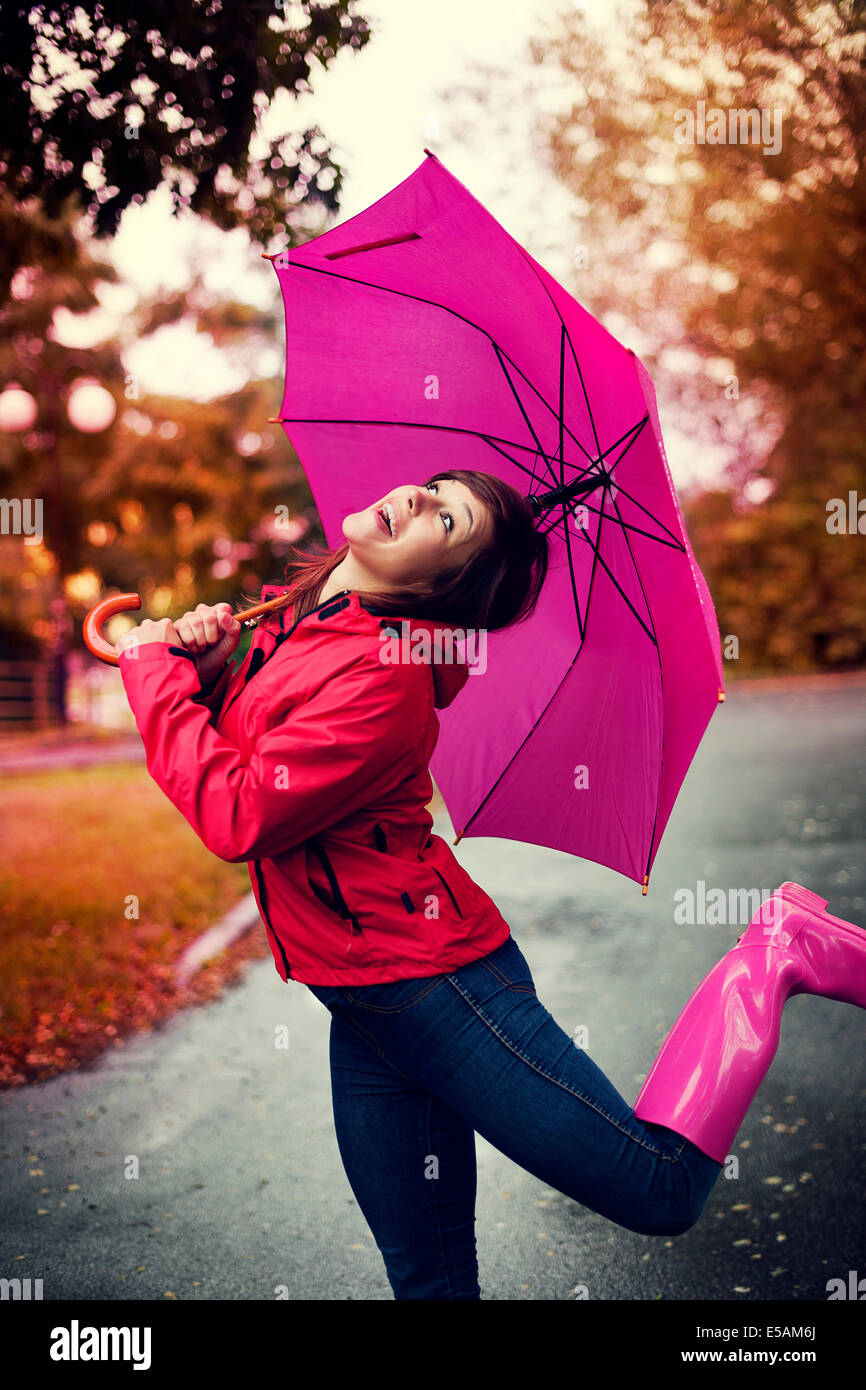 Cheerful woman with umbrella and rubber boots in the rain Debica, Poland Stock Photo