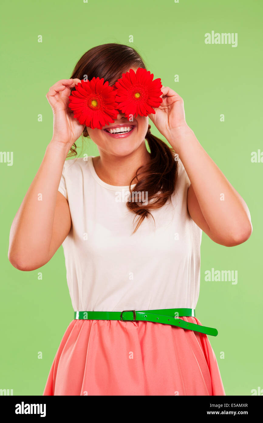 Smiling woman covering her eyes with two flowers, Debica, Poland Stock Photo