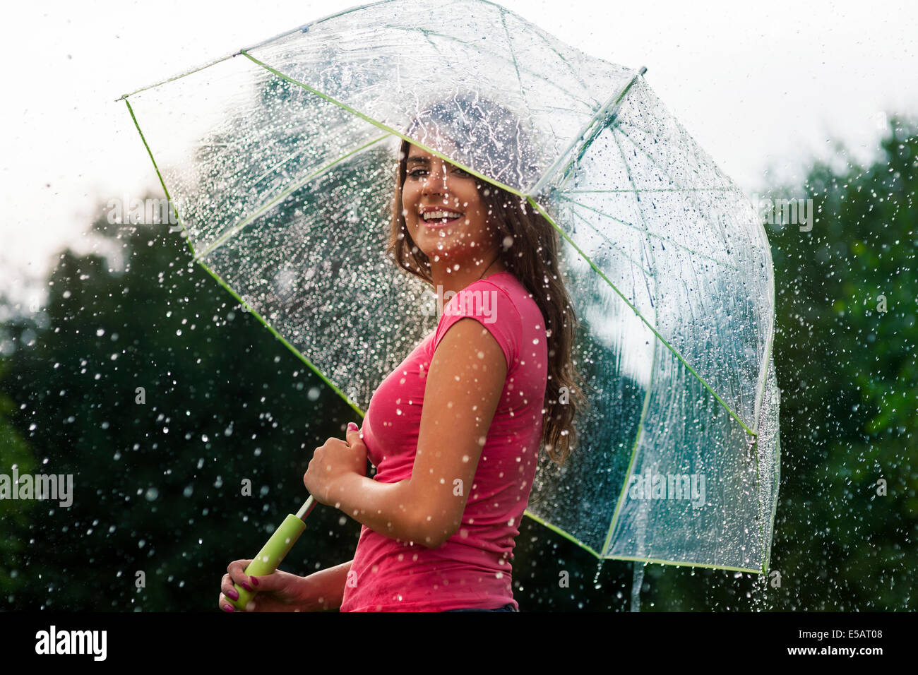 Young woman standing in summer rain with umbrella  Debica, Poland Stock Photo