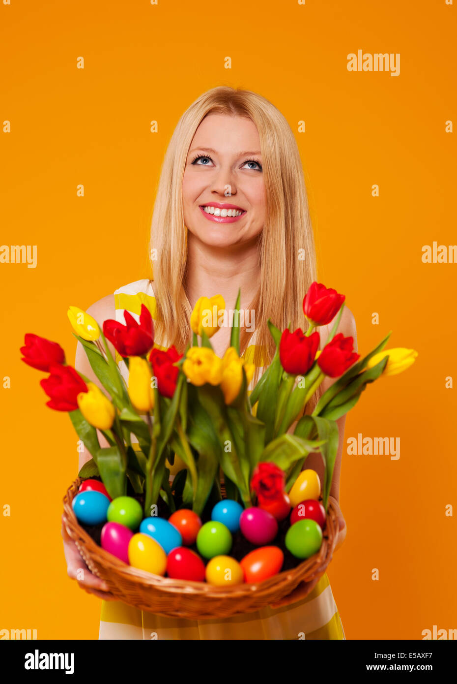 Happy woman holding basket with spring flower and Easter eggs Debica, Poland Stock Photo