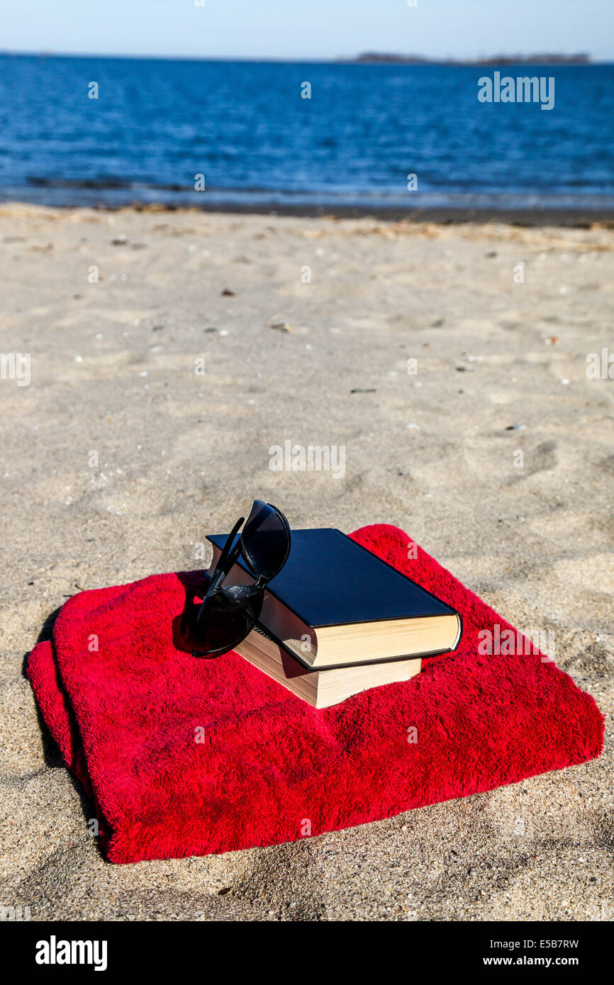 Book on beach with red towel and sand Stock Photo