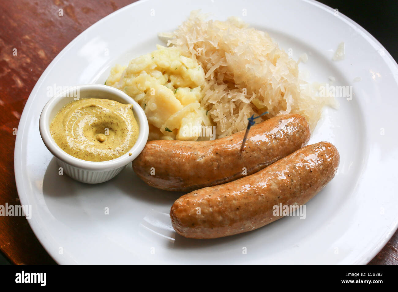 Bratwurst on plate with German potato salad, mustard and sauerkraut Stock Photo
