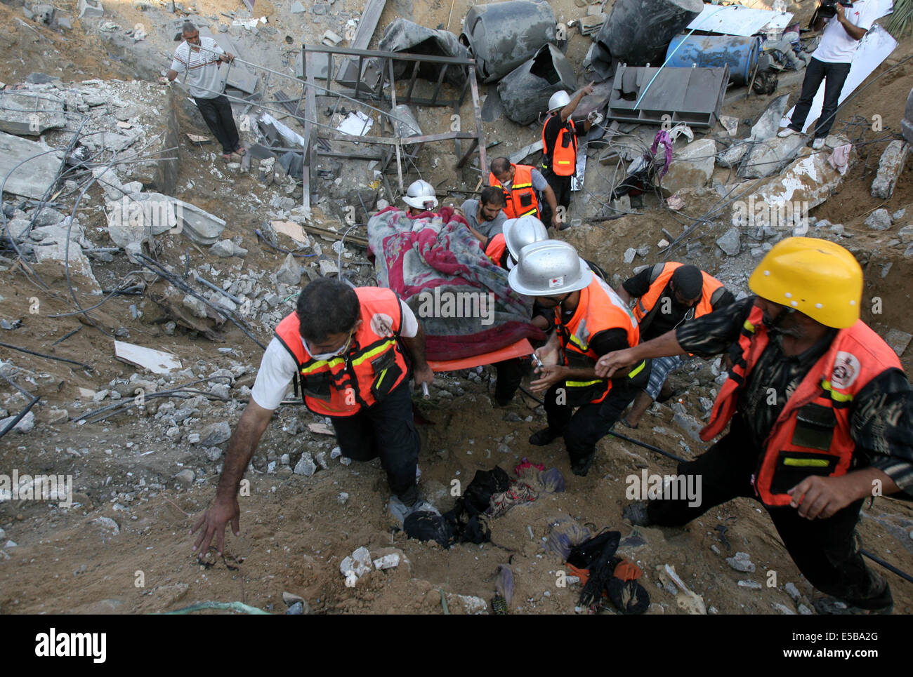 Khan Younis, Khan Younis, Palestinian Territory. 26th July, 2014. Palestinian rescue workers use an excavator to remove a dead body after what witnesses said was an Israeli air strike on the al-Najar family house in Khan Younis in the southern Gaza Strip July 26, 2014. A 12-hour humanitarian truce went into effect on Saturday after Israel and Palestinian militant groups in the Gaza Strip agreed to a U.N. request for a pause in fighting and efforts proceeded to secure a long-term ceasefire moved ahead. Stock Photo