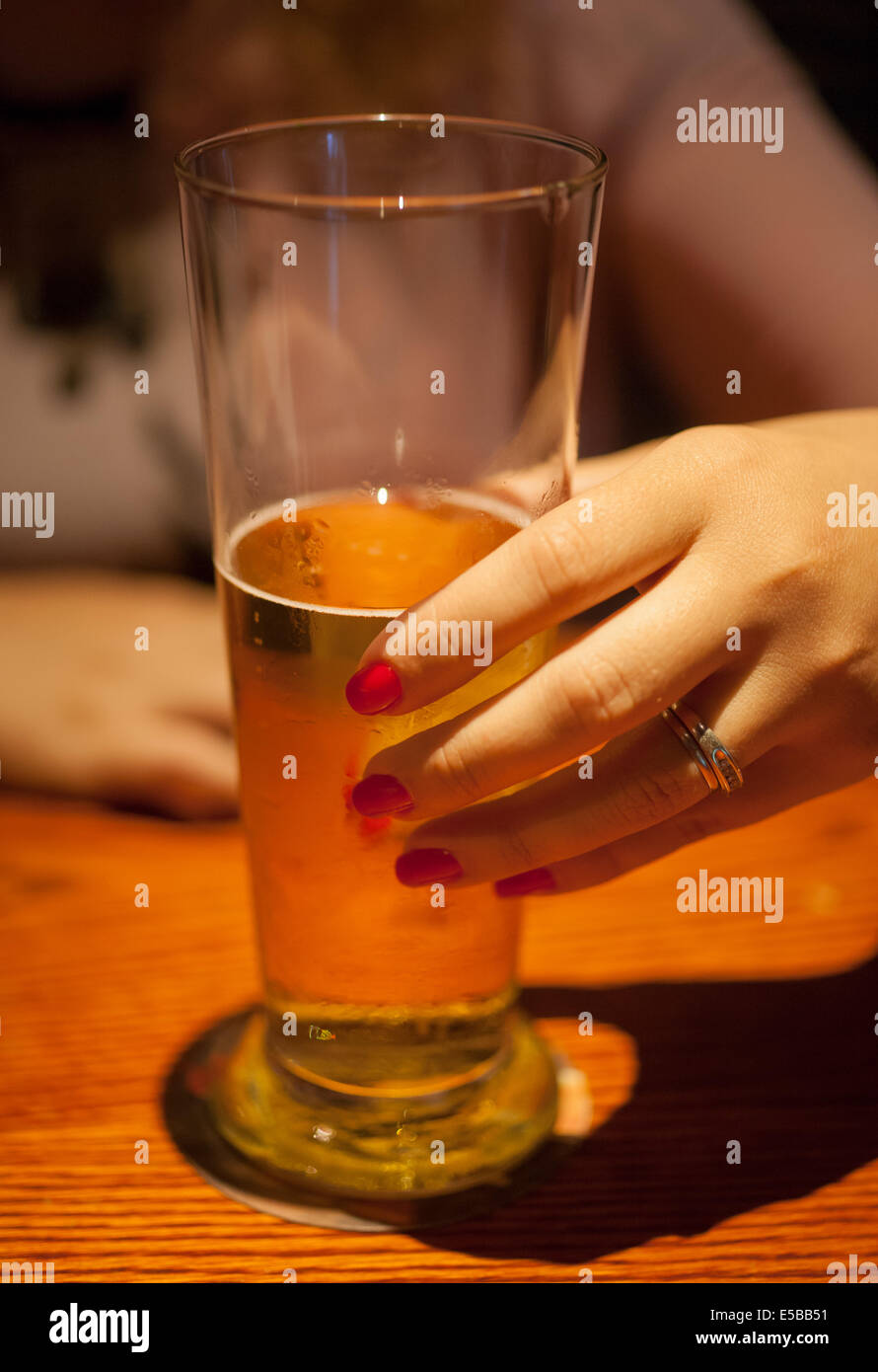 A woman's hand holding a glass of beer Stock Photo
