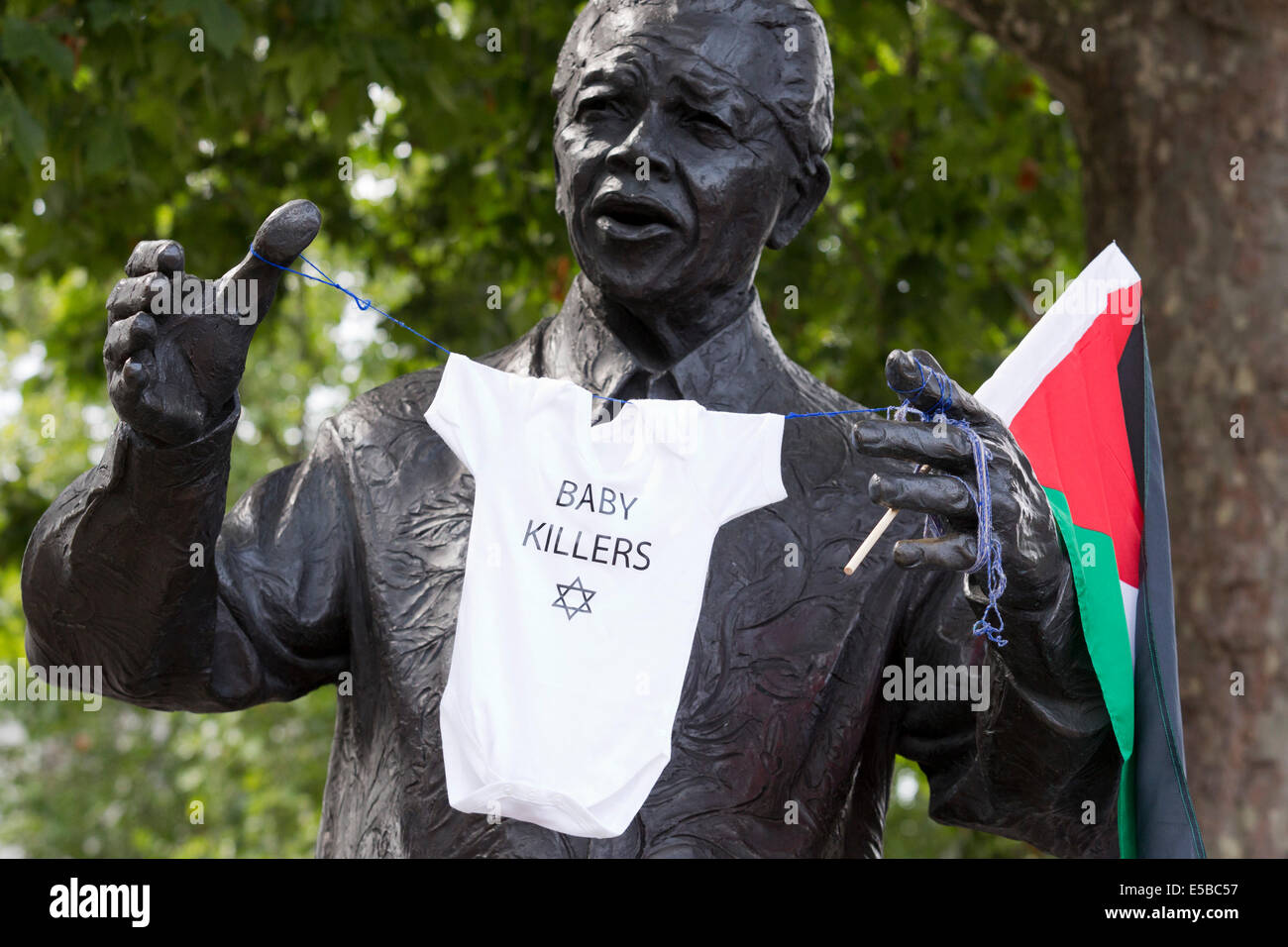 London, UK. 26 July 2014. Protesters have attached a Palestinian flag and a baby romper with the wording 'Baby Killers' and the Star of David to the Nelson Mandela statue in Parliament Square. Protesters gather in Parliament Square and Whitehall after a march from the Israeli Embassy in Kensington to call for an end to the Israeli military action against the Palestinians in the Gaza Strip at a political rallye. Credit:  Nick Savage/Alamy Live News Stock Photo