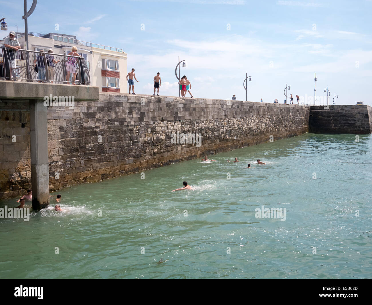 Teenagers gather on Portsmouth Hotwalls to dive into the sea. Despite warning notices around the area and increased patrols the practice continues on hot days Stock Photo