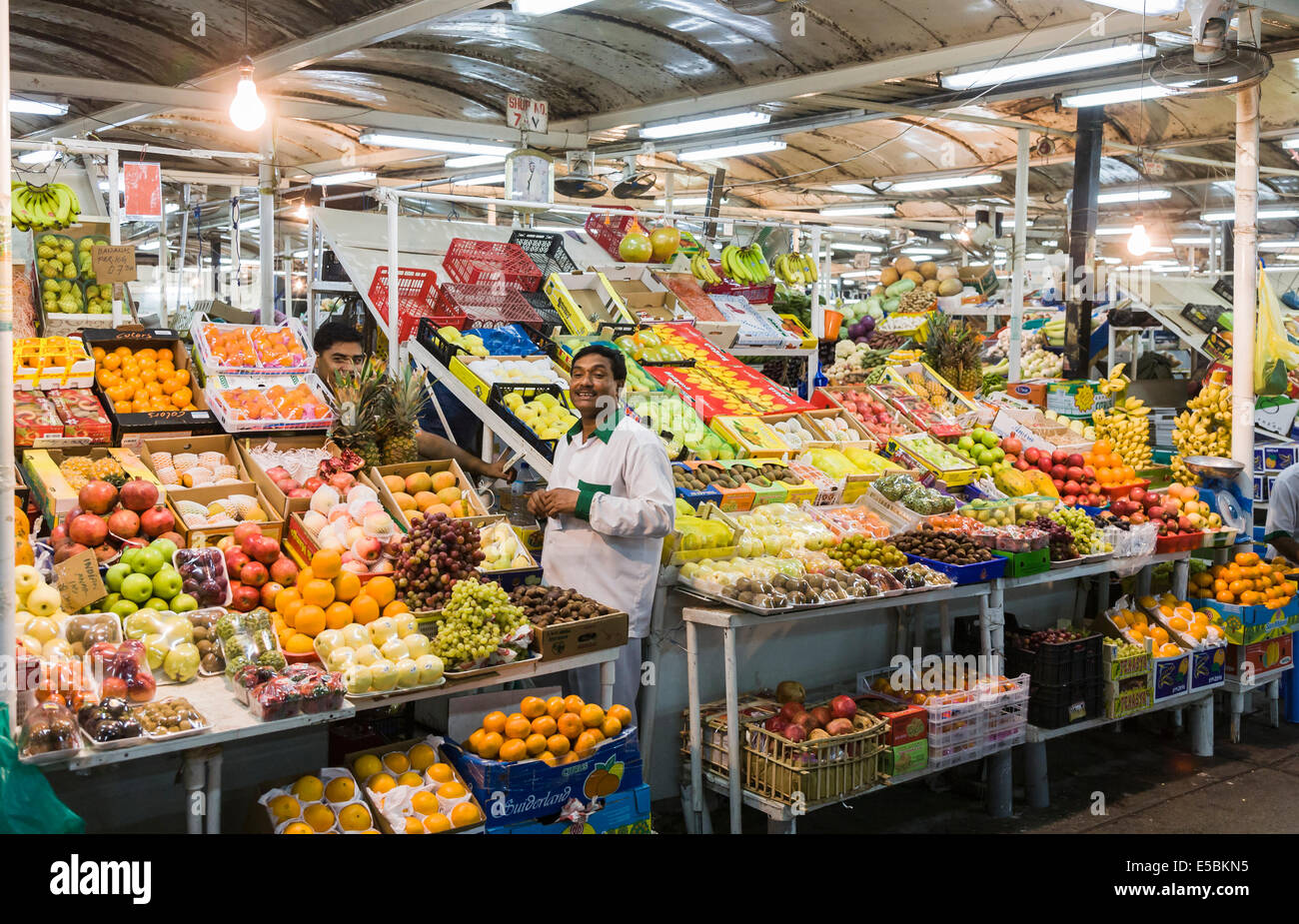 Stallholder arranges the produce on a stall selling colourful fruit and vegetables at the market by the fish souk, Deira, Dubai Stock Photo