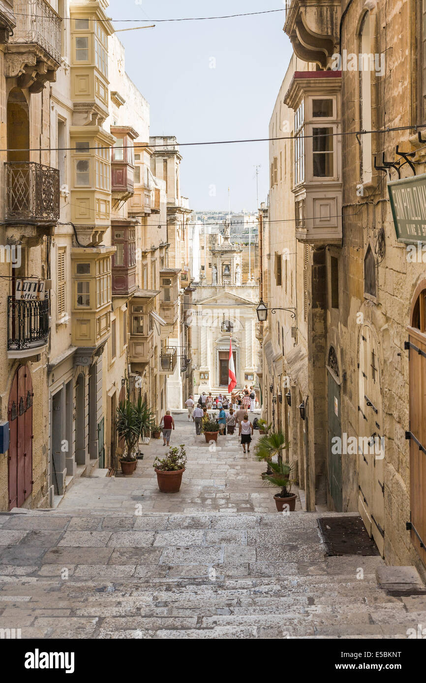 Narrow pedestrianised paved street in downtown Valletta, Malta, with flagstone stone steps and historical buildings Stock Photo