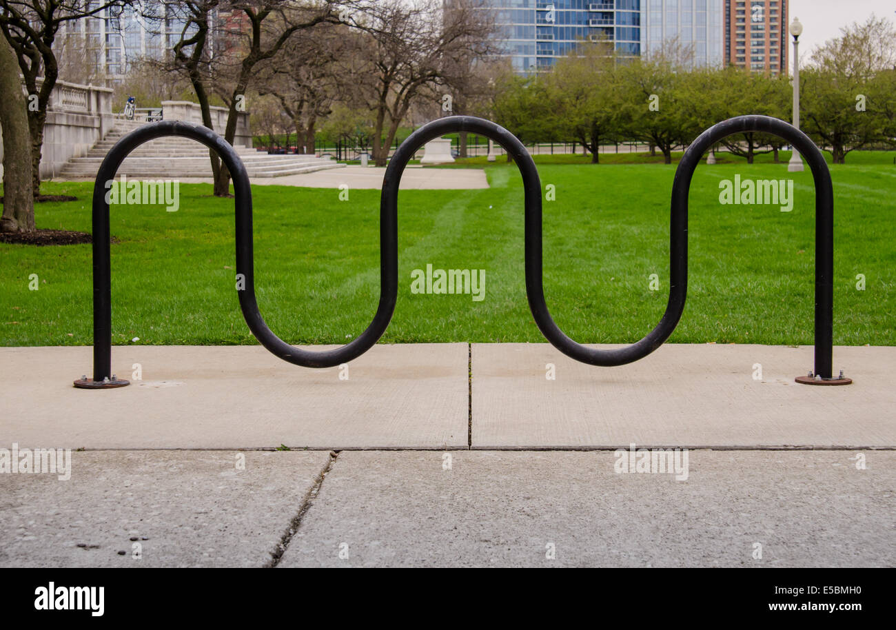 A bike rack sits in front of green grass in a public space Stock Photo