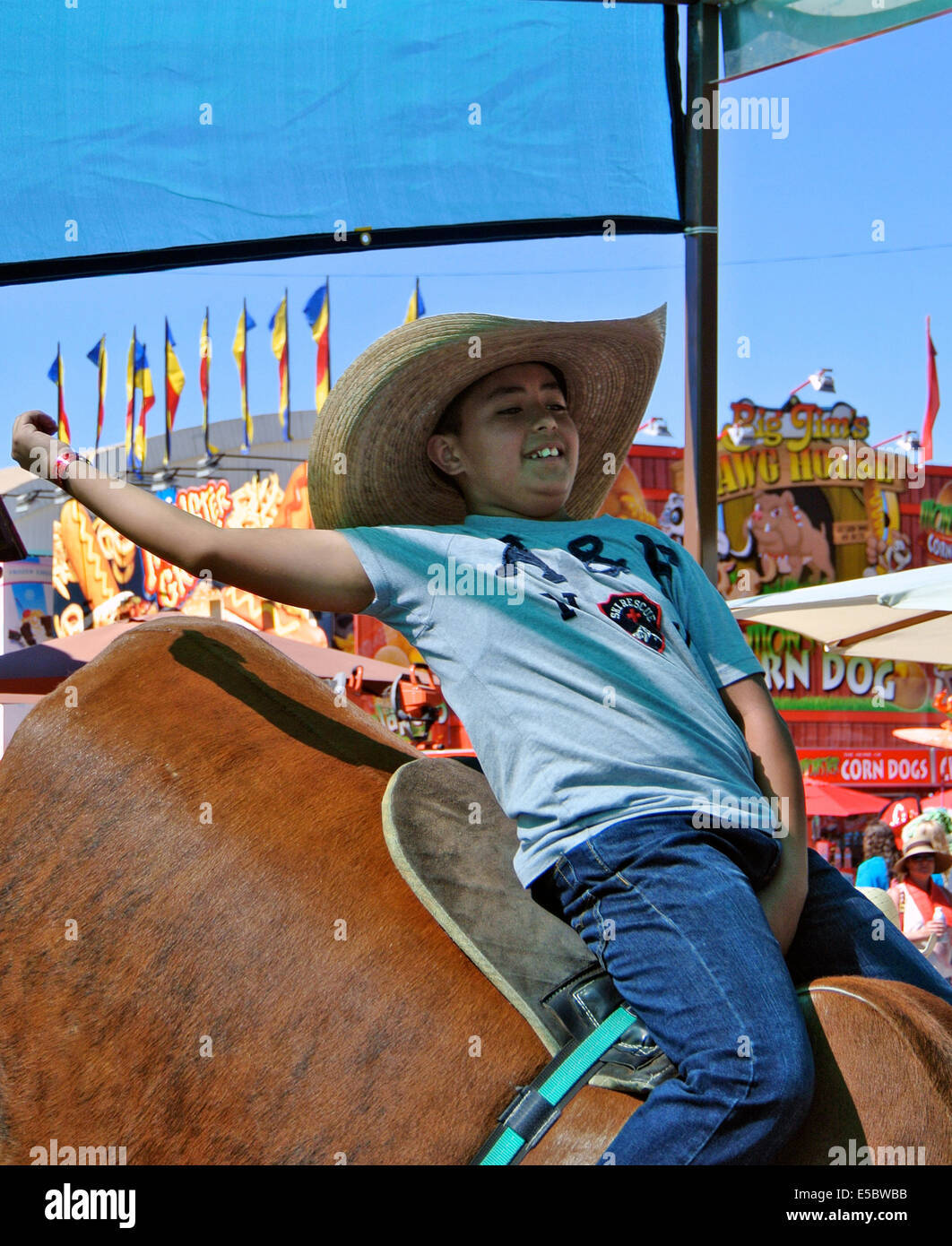 Santa Rosa, California, USA. 26th July, 2014. July 26th Santa Rosa California. Mexican American  boy wearing cowboy hat waves arm in the air in victory after riding mechanical bull ride at Sonoma County fair in Santa Rosa California USA Credit:  Bob Kreisel/Alamy Live News Stock Photo