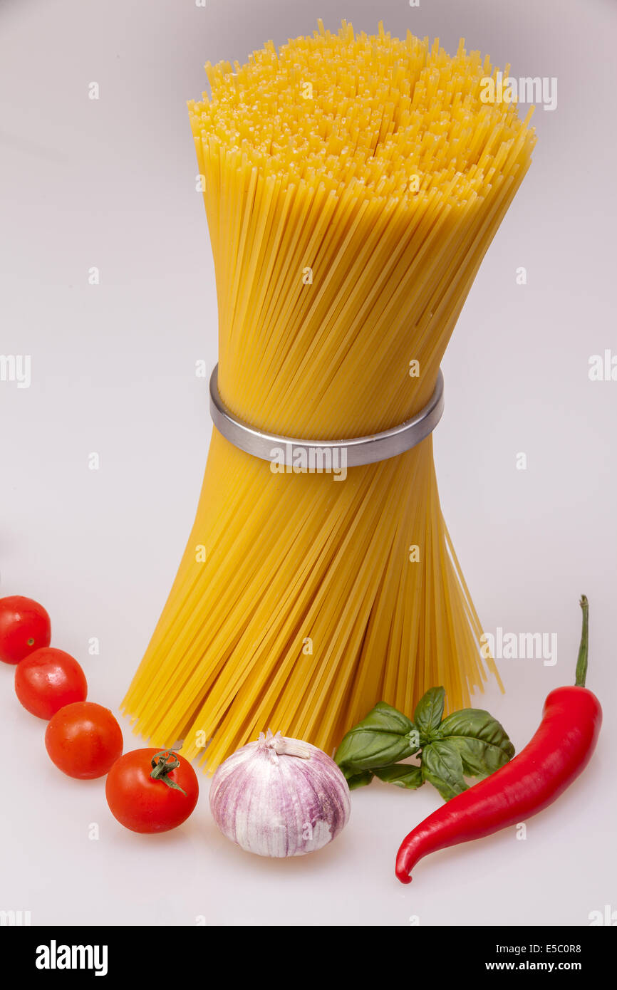 Spaghetti standing with fresh spices and vegetables, raw Stock Photo